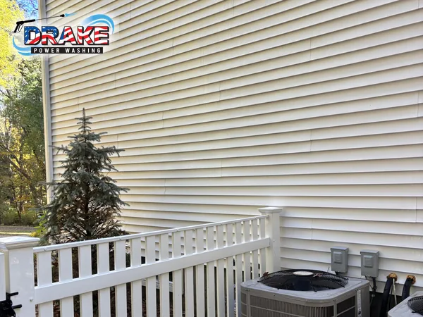 Clean vinyl siding beside a white railing and AC units after house washing in Franklin MA